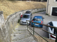 La strada finisce dove comincia il parcheggio Automobile parcheggiata davanti a una scalinata pedonale nei pressi della Fontana Luminosa all’Aquila.