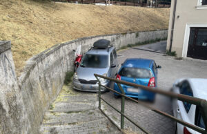 La strada finisce dove comincia il parcheggio Automobile parcheggiata davanti a una scalinata pedonale nei pressi della Fontana Luminosa all’Aquila.
